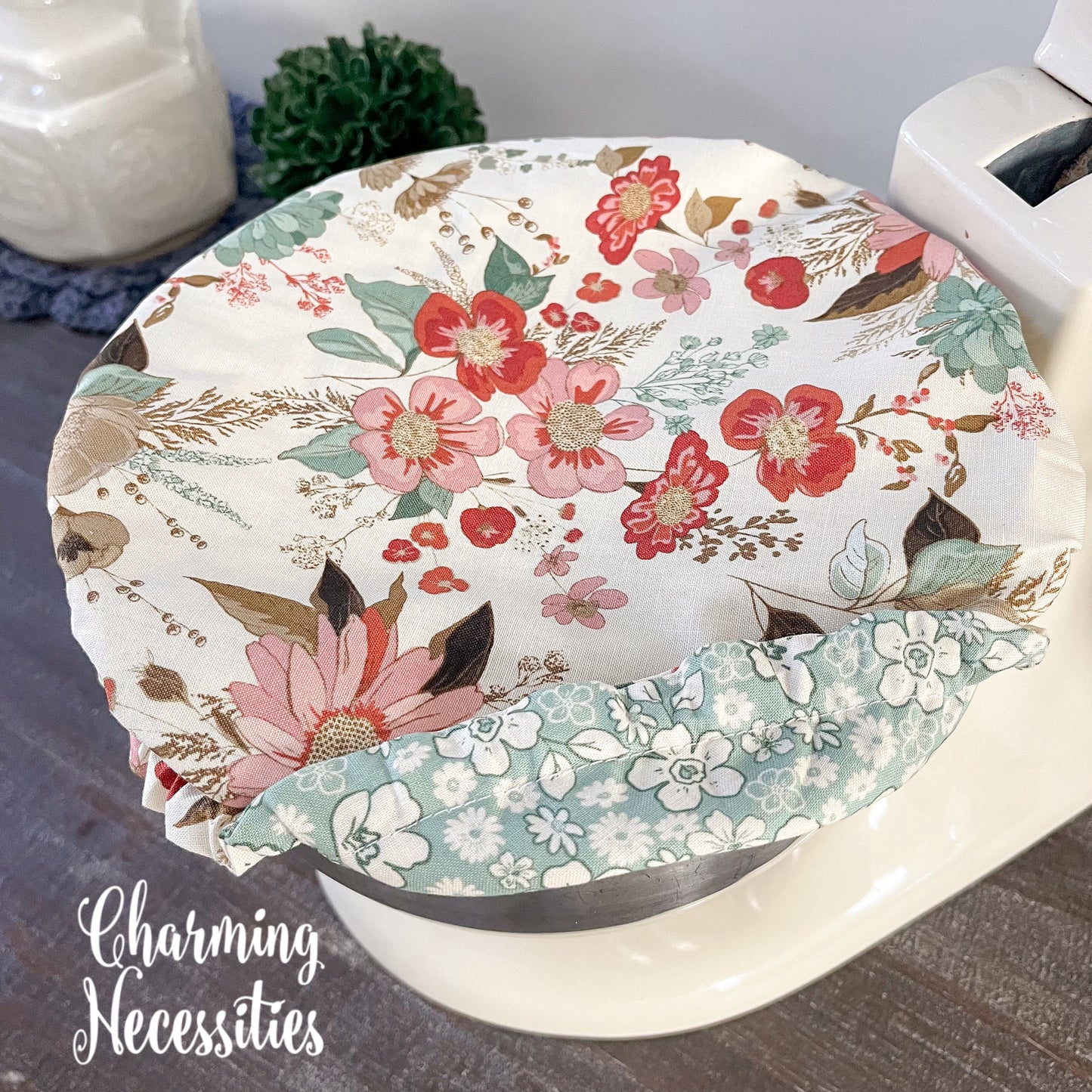 Neutral Floral-patterned bowl cover with 'Charming Necessities' branding.
