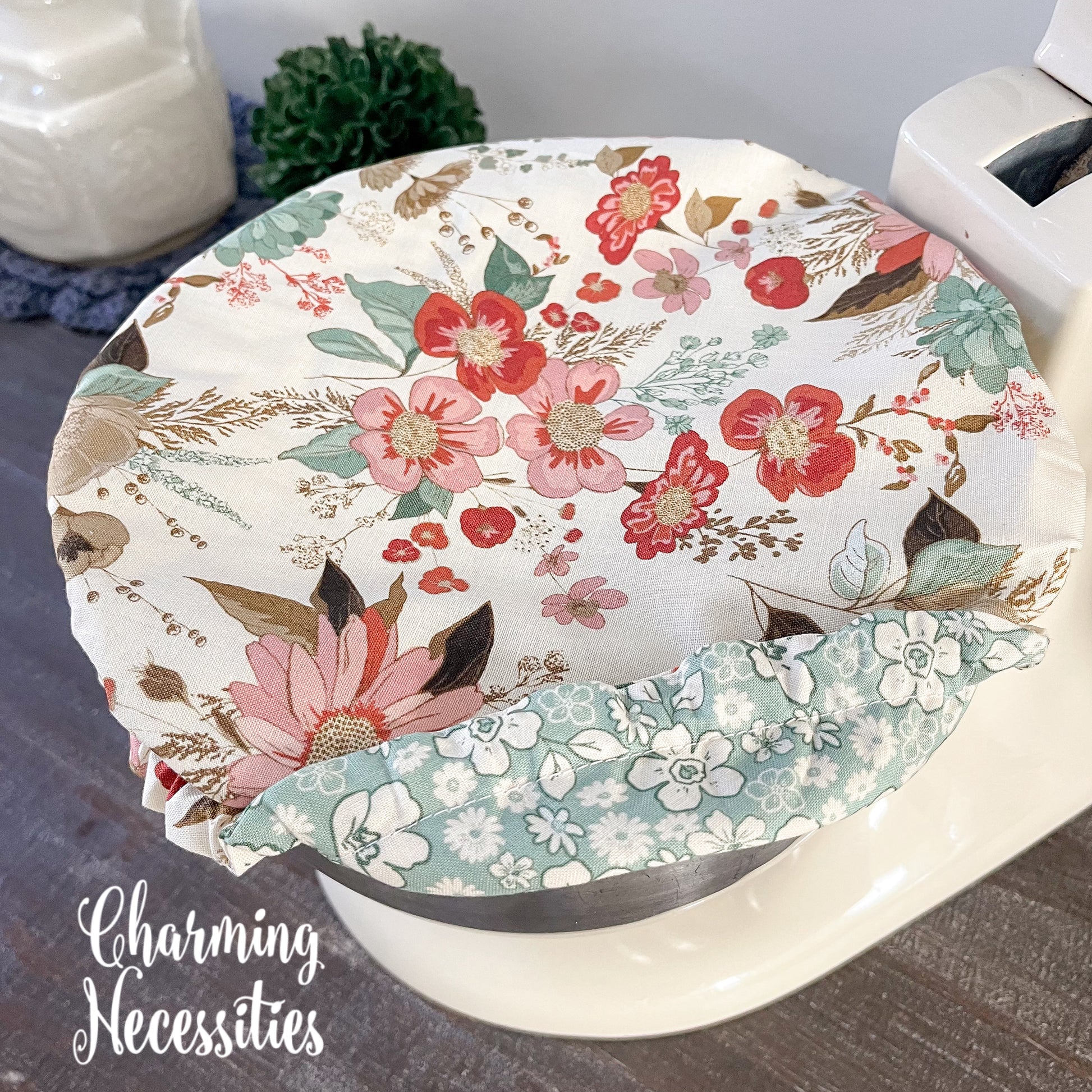 Neutral Floral-patterned bowl cover with 'Charming Necessities' branding.