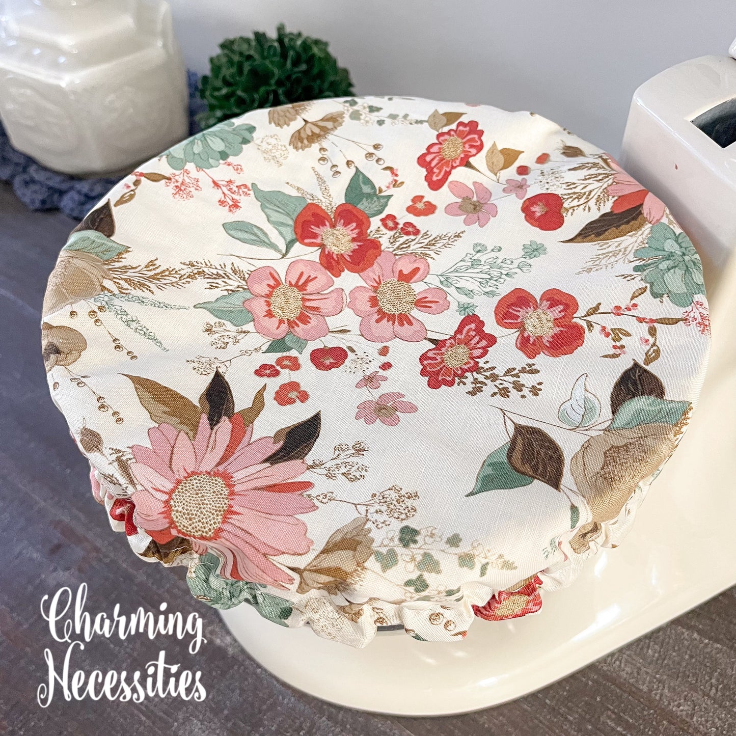 neutral Floral-patterned bowl cover on a wooden surface with 'Charming Necessities' branding.