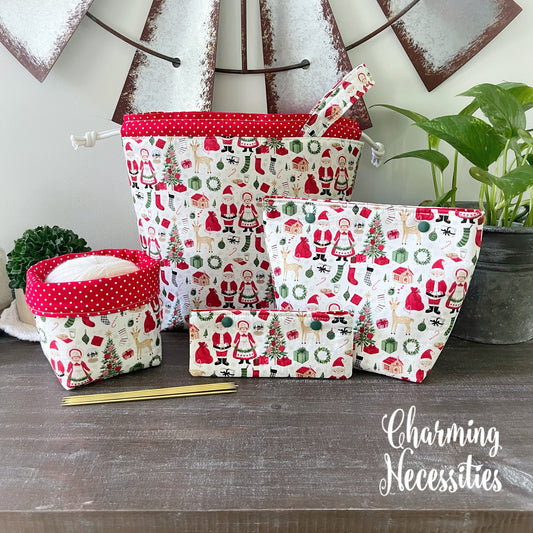 Set of fabric knitting project bags with Christmas patterns on a wooden surface, featuring the brand 'Charming Necessities'.