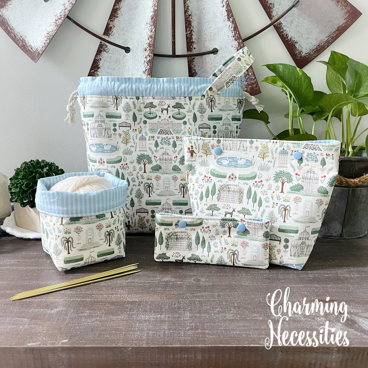 Set of fabric project bags with nature-themed design on a wooden surface, with 'Charming Necessities' branding.