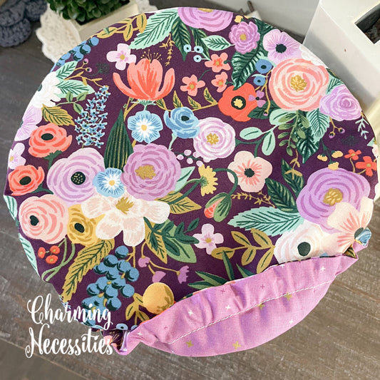 Floral-patterned bowl cover with colorful flowers on a dark purple background, branded 'Charming Necessities'.