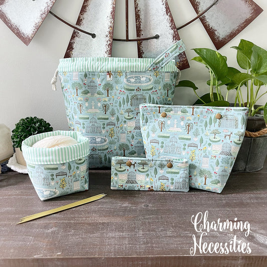 Set of regency themed fabric project bags with nature-themed design on a wooden surface, featuring the brand 'Charming Necessities'.